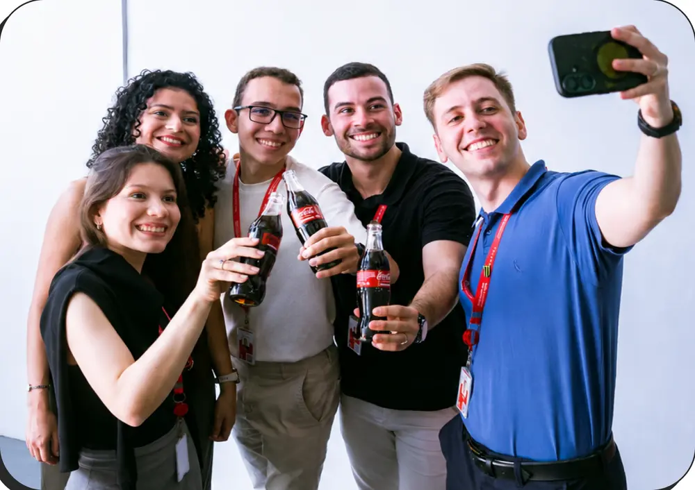 Grupo de cinco jovens da Solar Coca-Cola tirando uma selfie com garrafas de Coca-Cola